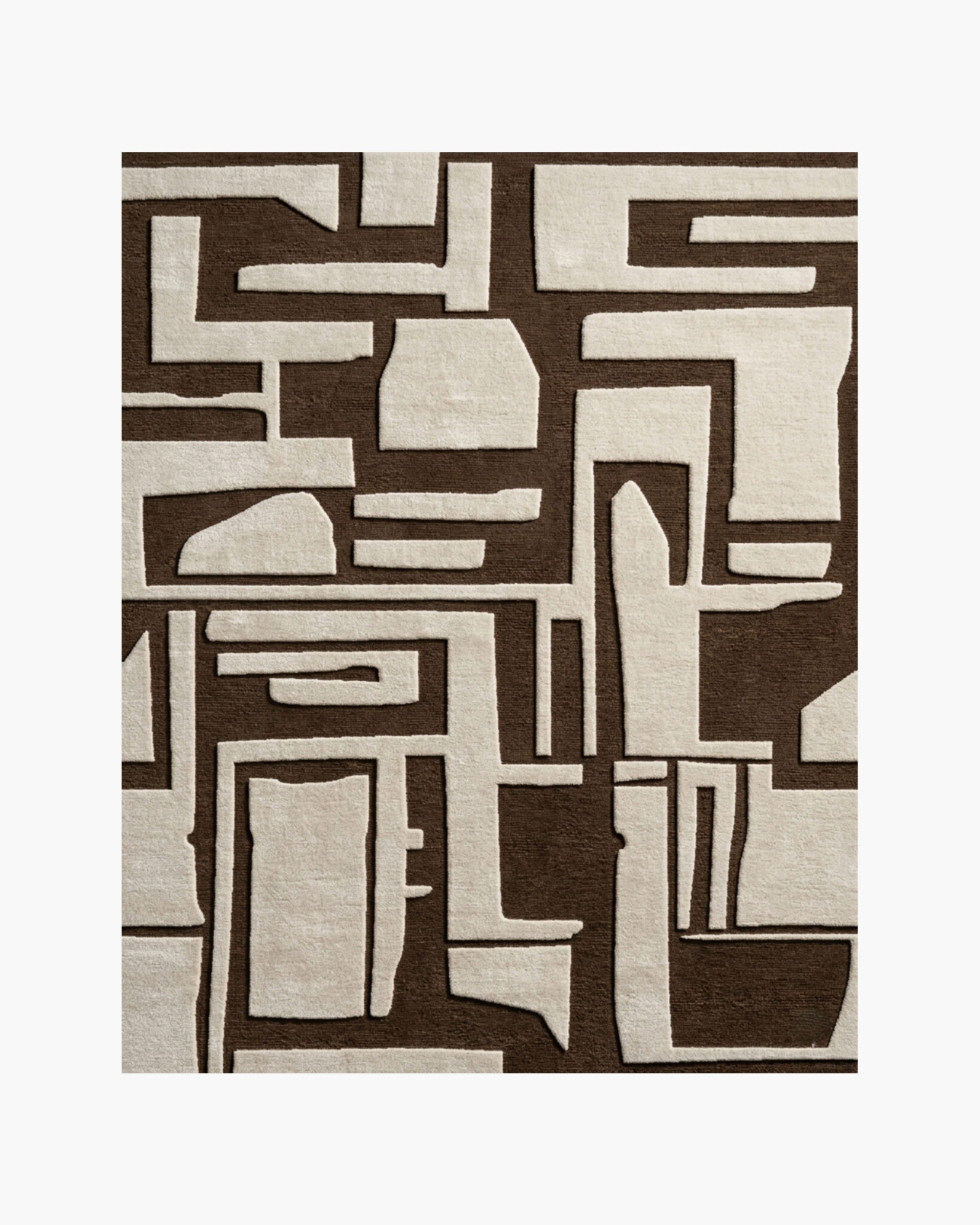 Adobe Glyph brown and cream tribal geometric wool rug with carved maze-like shapes on a chocolate-brown ground