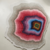Geode Bloom organic multicolor wool rug with concentric geode-like rings in pink, blue, gold and grey