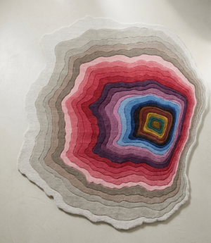 Geode Bloom organic multicolor wool rug with concentric geode-like rings in pink, blue, gold and grey